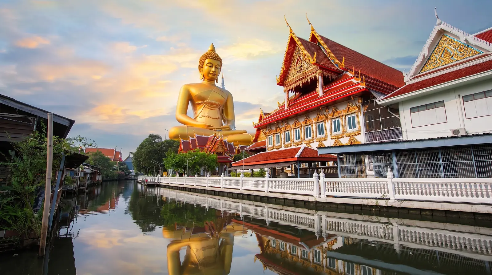Gran Buda dorado junto a un templo y un canal en Tailandia